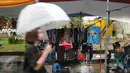 Beberapa pengunjung melintas di antara deretan stand produk pada Festival Kemang yang berlangsung di Jalan Kemang Raya, Jakarta (7/11/2015). Hujan deras disertai angin kencang mewarnai Festival Kemang hari pertama. (Liputan6.com/Helmi Fithriansyah)