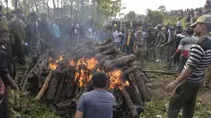 Polisi dan pekerja kehutanan bersama penduduk desa menyaksikan tubuh gajah dibakar setelah kereta penumpang melaju menabrak dua gajah yang melintasi rel di desa Batasi dekat perbatasan India-Nepal, sekitar 37 km dari Siliguri (11/12/2019). (AFP/Diptendu Dutta)