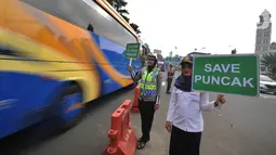 Petugas kepolisian dan Badan Pengelola Transportasi Jabodetabek (BPTJ) berdiri sambil membawa papan imbauan saat uji coba sistem kanalisasi 2-1 Jalur Puncak di kawasan Gadog, Bogor, Jawa Barat, Minggu (27/10/2019). (merdeka.com/Arie Basuki)