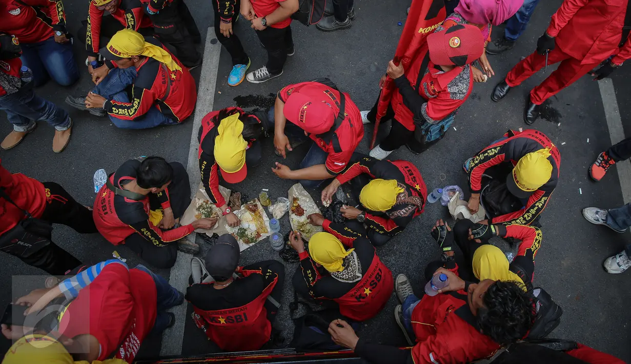 Buruh beristirahat sambil makan siang disela aksi demo di kawasan Istana Negara, Jakarta, Kamis (15/9). Ribuan buruh dari berbagai elemen organisasi menyatakan penolakan mereka terhadap paket kebijakan ekonomi jilid IV. (Liputan6.com/Faizal Fanani)