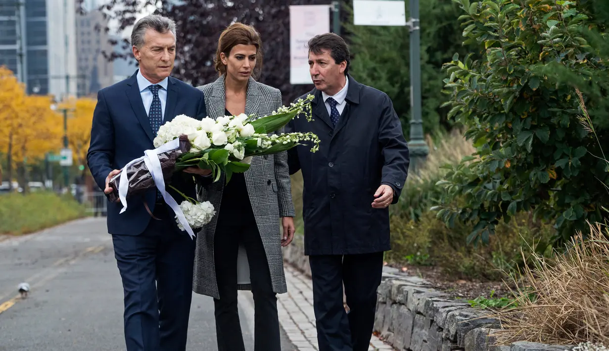 Presiden Argentina, Mauricio Macri didampingi Ibu Negara, Juliana Awada saat akan meletakkan karangan bunga di lokasi serangan truk pikap di New York, Selasa (7/11). Lima dari delapan korban meninggal adalah warga Argentina. (AP Photo/Craig Ruttle)