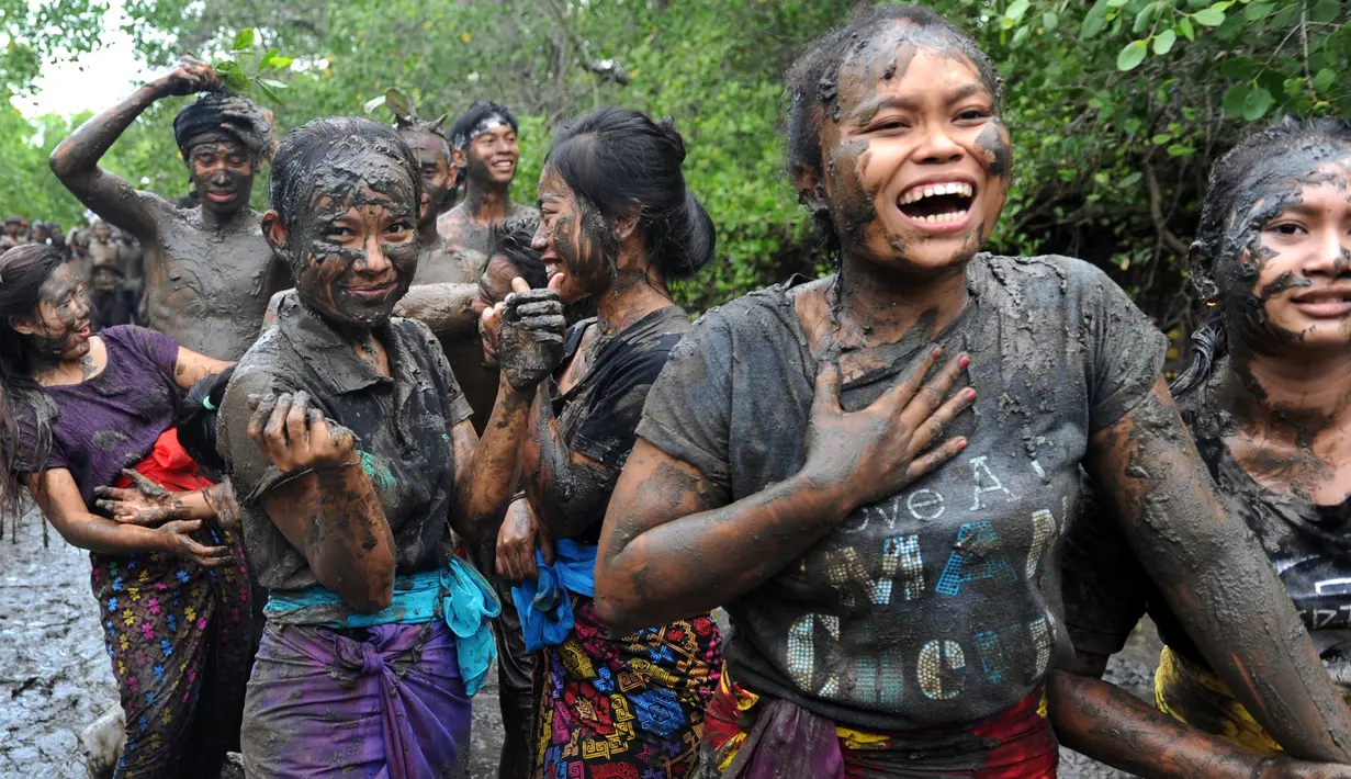 Sejumlah wanita Bali terlihat bergembira saat mengikuti tradisi mandi lumpur di desa Kedonganan, Denpasar, Bali (10/3). Mebuug-buugan bertujuan untuk menetralkan sifat-sifat buruk usai hari raya Nyepi. (AFP/Sonny Tumbelaka)