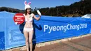 Seorang aktivis wanita dari PETA berunjuk rasa di samping spanduk Olimpiade Pyeongchang 2018 di Pyeongchang, Korea Selatan (6/2). Aktivis ini nekat tampil berbikini saat unjak rasa berlangsung. (AFP Photo/Dimitar Dilkoff)