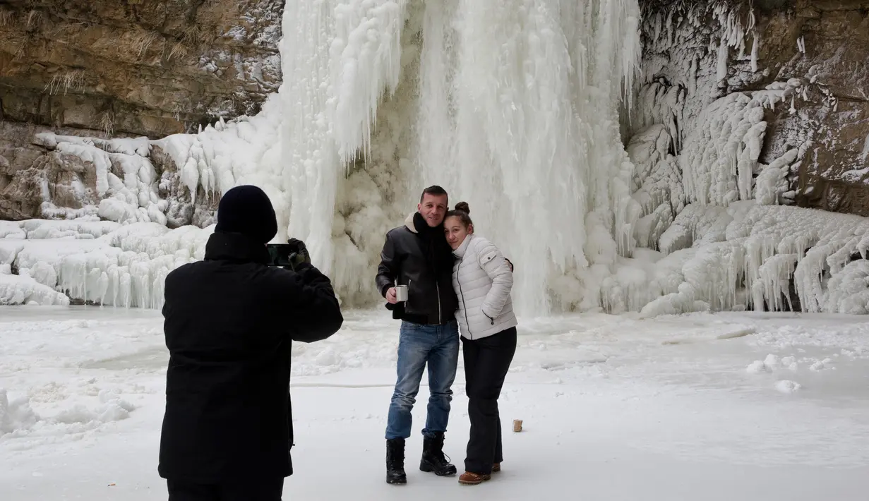 Pengunjung berpose di depan air terjun Mirusha yang membeku di Lapceve, Kosovo (9/1). Ekstremnya cuaca yang melanda sebagian eropa menyebabkan puluhan orang tewas dan keberangkatan pesawat di tunda. (AP Photo/Visar Kryeziu)