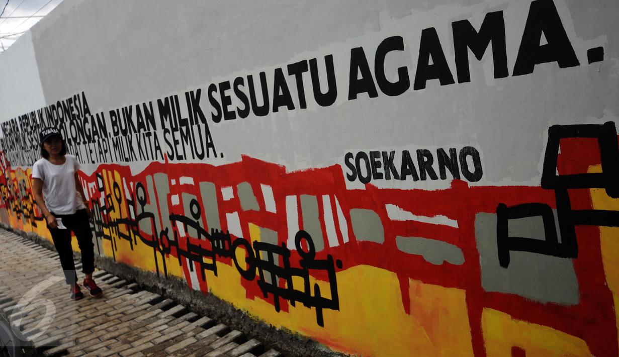 Warga melintas di depan tulisan toleransi di Lapangan Kebagusan, Jakarta, Rabu (15/2). Jelang menggunakan hak pilihnya pada Pilkada, Ketua Umum PDI-P Megawati Soekarnoputri menggoreskan tinta pada salah satu gambar. (Liputan6.com/Helmi Fithriansyah)