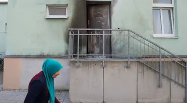 Seorang wanita berhijab melintas di pintu Masjid Fatih Camii yang rusak akibat serangan bom di Dresden, Jerman Timur, Senin (26/9) malam. Tidak ada korban namun terdapat kerusakan di bangunan masjid akibat getaran ledakan itu. (SEBASTIAN KAHNERT/DPA/AFP)