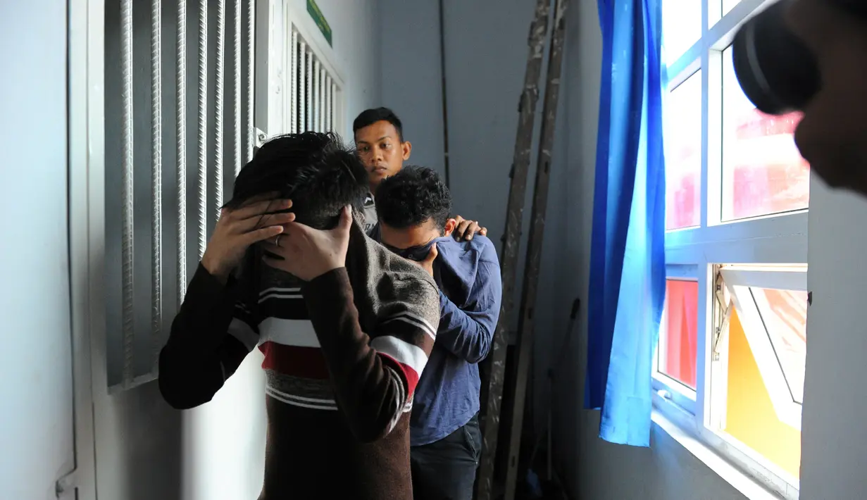 Terdakwa pasangan sejenis (gay) menutupi wajahnya saat dibawa untuk menjalani persidangan di pengadilan syariah di Banda Aceh (17/5). Majelis hakim Mahkamah Syar'iyah Banda Aceh memvonis terdakwa dengan 85 kali cambuk. (AFP/Chaideer Mahyuddin)