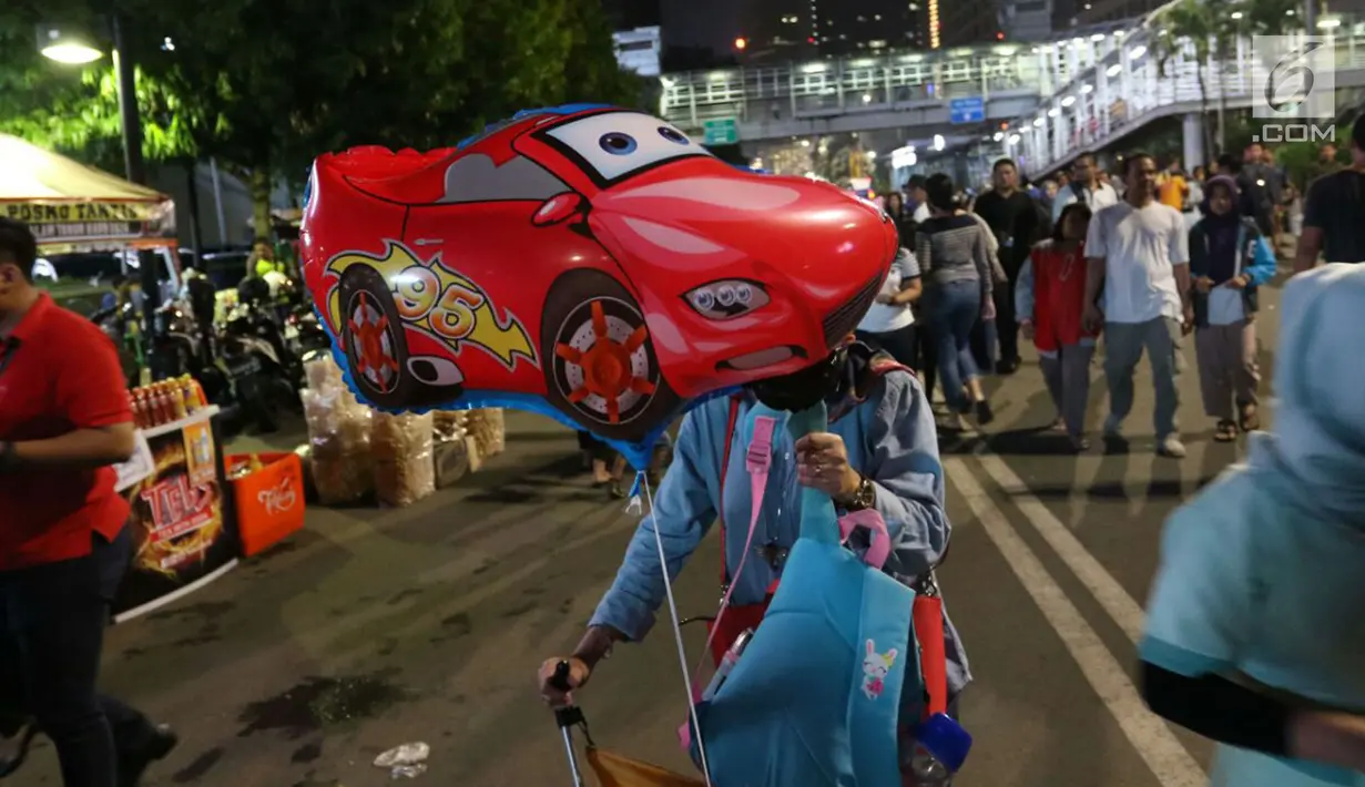 Warga membawa balon mobil di Jalan MH Thamrin, Jakarta, Minggu (31/12). Pemprov DKI Jakarta memberlakukan car free night mulai pukul 19.00–24.00 WIB.  (Liputan6.com/Angga Yuniar)