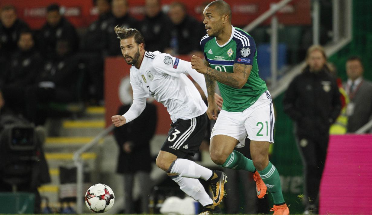 Striker Irlandia Utara, Josh Magennis, berusaha melewati bek Jerman, Marvin Plattenhardt, pada laga Kualifikasi Piala Dunia 2018 di Stadion Windsor Park, Kamis (5/10/2017). Jerman menang 3-1 atas Irlandia Utara. (AP/Peter Morrison)