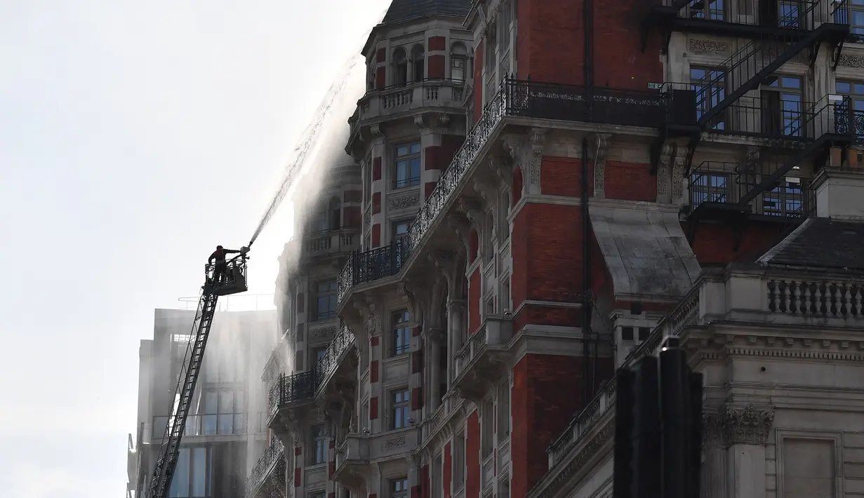 Petugas pemadam kebakaran berusaha menjinakkan kobaran api di hotel Mandarin Oriental, London, Inggris, Rabu (6/6). Laporan menyebutkan kebakaran terjadi di atap hotel bintang lima tersebut. (AFP / Ben STANSALL)