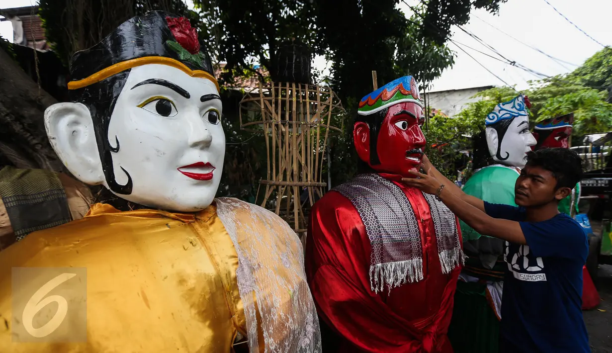 Pengrajin memperbaiki wajah ondel-ondel yang selesai dibuat di kawasan Kramat, Jakarta, Kamis (26/1). Ondel-ondel merupakan kesenian tradisional Betawi yang biasa ditampilkan dalam pesta-pesta atau hajatan. (Liputan6.com/Faizal Fanani)