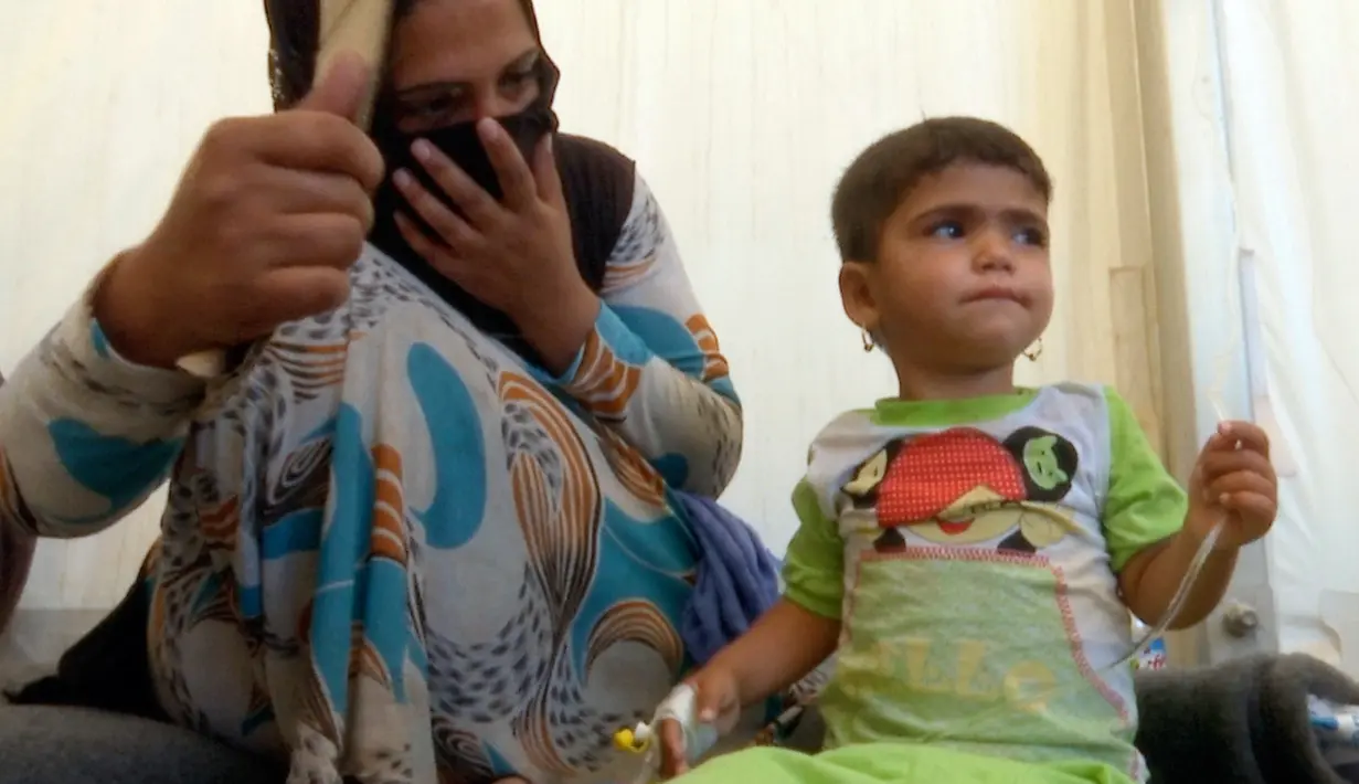 Seorang ibu melihat putrinya saat dirawat di kamp Hassan Sham U2, Irak (13/6). Menteri kesehatan Irak, Adila Hamoud mengatakan kepada The Associated Press di Baghdad 752 orang jatuh sakit dan setidaknya dua orang meninggal. (AP Photo/Balint Szlanko)