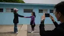Dua anak berpose menirukan jabat tangan Presiden Korea Selatan Moon Jae In dengan Pemimpin Korea Utara Kim Jong Un di replika desa perbatasan DMZ Panmunjom di Namyangju, Sabtu (5/5). Replika Panmunjom menjadi wisata baru setelah KTT Korea. (AFP/Ed JONES)