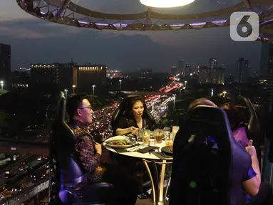 Pengunjung menyantap hidangan di Lounge in the sky, Jakarta, Selasa (29/3/2022). Lounge in the sky merupakan restoran dengan menyajikan sensasi menyantap hidangan dari atas ketinggian dengan pemandangan cakrawala 360 derajat Jakarta. (Liputan6.com/Herman Zakharia)