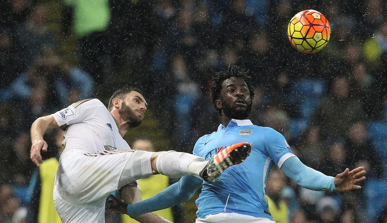 Pemain Swansea City, Angel Rangel (kiri), berebut bola dengan pemain Manchester City, Wilfried Bony, dalam lanjutan Liga Inggris di Stadion Etihad, Manchester, Sabtu (12/12/2015). (AFP/Lindsey Parnaby)