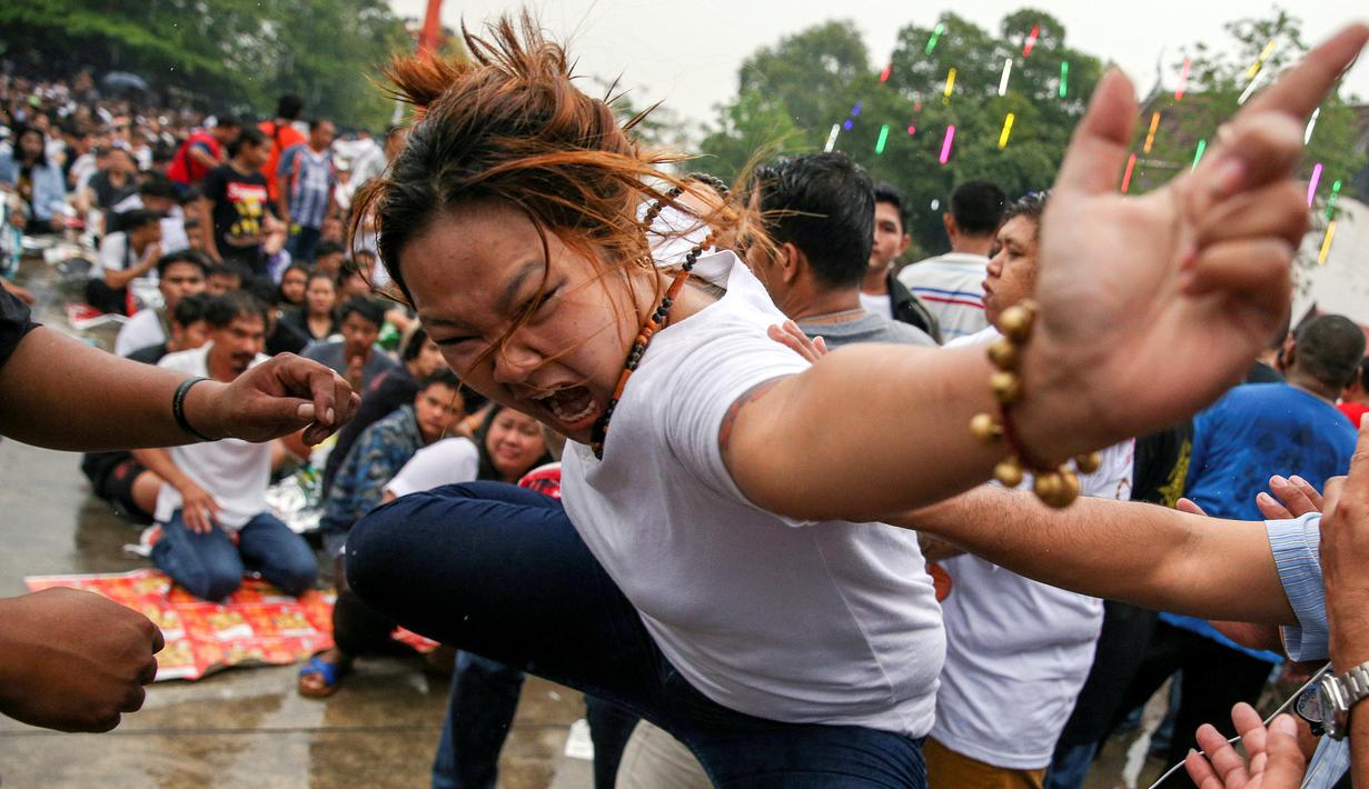 Seorang wanita kesurupan meniru binatang buas selama Festival Tato Suci di kuil Wat Bang Phra, Nakhon Pathom, Thailand (16/3). Acara tahunan ini digelar untuk mengisi ulang kekuatan tato suci di tubuh mereka. (Reuters/Athit Perawongmetha)