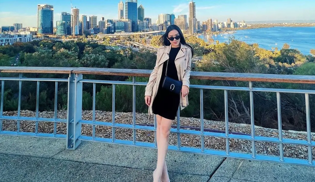 Saat liburan, Kusuma Puteri mengenakan mini dress hitam dipadukan dengan coat coklat panjang sambil membawa sling bag Gucci warna hitam dari model Dionysus.  [@kusumaputeri]