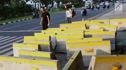 Pejalan kaki menghindari beton pembatas jalan yang diletakkan di atas trotoar Jalan Medan Merdeka Utara, Jakarta, Kamis (25/7/2019). Pembatas jalan yang berada tidak pada tempatnya mengganggu kenyamanan pejalan kaki yang melintasi trotoar jalan tersebut. (Liputan6.com/Helmi Fithriansyah)