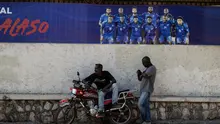 Dua pria beristirahat di depan spanduk Timnas Haiti yang akan mengikuti Piala Dunia 2026, di Petion-ville, Port-au-Prince, Haiti, pada 14 April 2026. Tim nasional Haiti lolos ke Piala Dunia 2026, yang kedua kalinya dalam sejarahnya. Sepak bola adalah olahraga paling populer di Haiti. (Clarens SIFFROY/AFP)