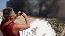 Seorang turis mengambil gambar kebakaran hutan di Benitatxell dekat Alicante, Spanyol, Senin (5/9). Sedikitnya 1.000 orang terpaksa diungsikan ke tempat yang lebih aman dari sejumlah vila. (REUTERS / Heino Kalis)