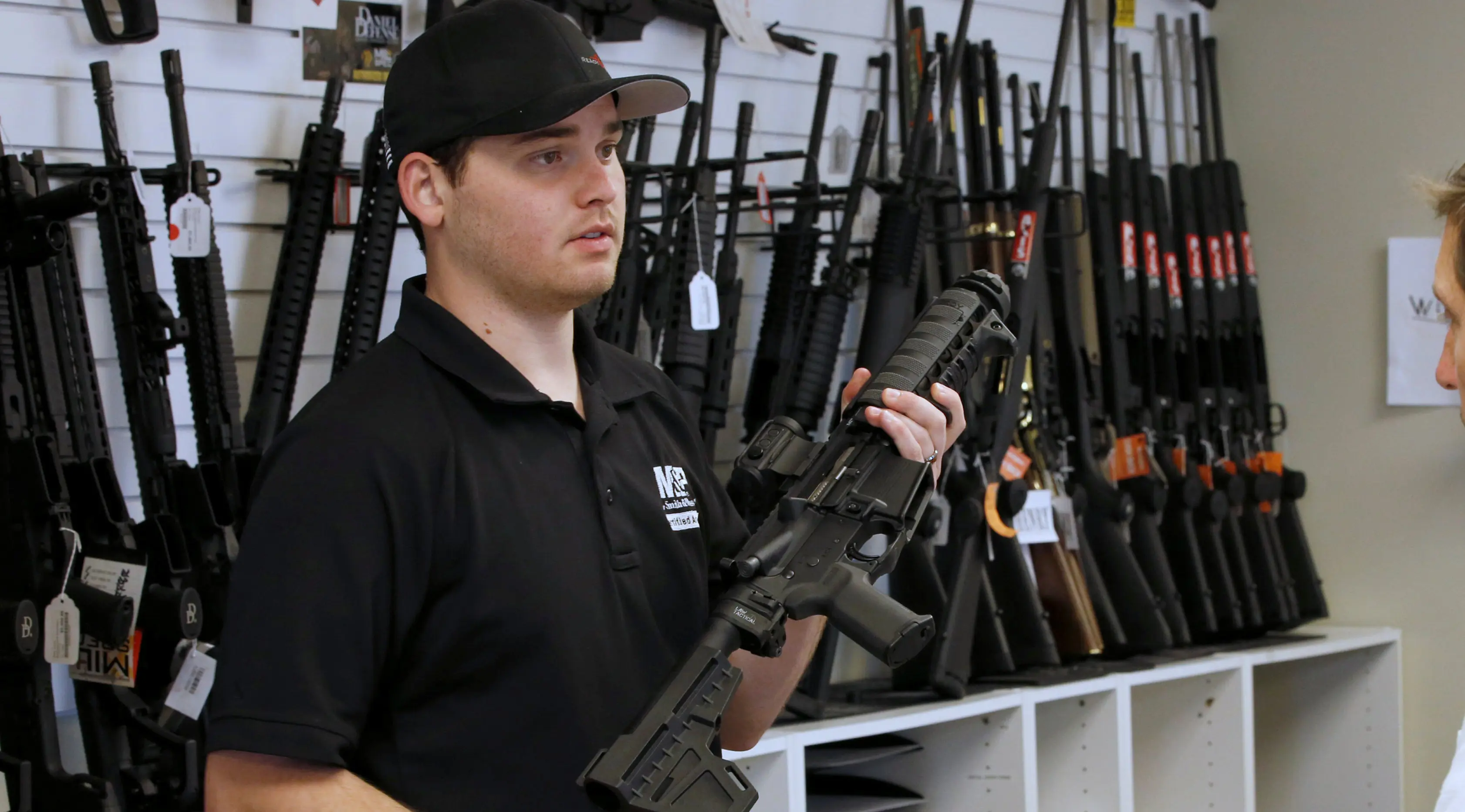 Penjaga toko senjata, Ryan Martinez  memegang senapan serbu AR-15 di toko senjata 