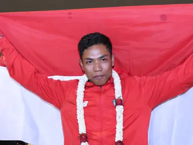 Pelari muda Indonesia, Lalu Muhammad Zohri membentangkan bendera Merah Putih saat penyambutan di Terminal 3 Bandara Soetta, Tangerang, Selasa (17/7). Lalu M Zohri meraih emas lari 100m putra di Kejuaraan Dunia U-20 IAAF. (Liputan6.com/Helmi Fithriansyah)