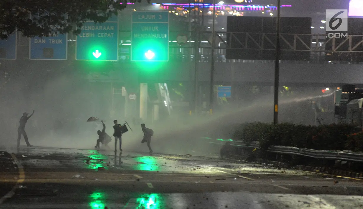 Mahasiswa mendapat semprotan water cannon dari aparat kepolisian saat berdemonstrasi menolak pengesahan RUU KUHP dan revisi UU KPK di kawasan Patal Senayan, Jakarta, Selasa (24/9/2019). Hingga malam ini, mahasiswa masih berpencar di kawasan Senayan. (merdeka.com/Arie Basuki)