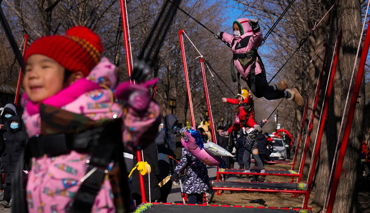 Anak-anak bermain trampolin saat orang-orang mengunjungi pekan raya kuil pada hari kedua perayaan Tahun Baru Imlek di Taman Yuanmingyuan, Beijing, China, Senin (23/1/2023). Tahun Baru Imlek adalah hari libur tahunan terpenting di China. (AP Photo/Andy Wong)