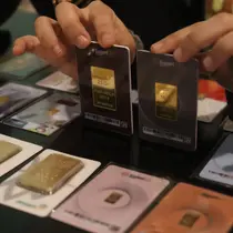 Karyawan menunjukkan kepingan emas yang dijual di Galeri 24, Jakarta, Selasa (15/12/2020). Harga emas hasil produksi PT Aneka Tambang Tbk (Antam) atau emas Antam kini turun Rp 1.000 per gram menjadi Rp 951 per gram pada perdagangan, Selasa (15/12). (Liputan6.com/Angga Yuniar)