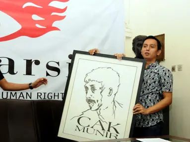 Direktur Imparsial Al Araf (kanan) memegang lukisan Munir jelang memberi keterangan di Jakarta, Selasa (6/9). Imparsial memandang pengungkapan kasus Munir adalah agenda penting penuntasan kasus pelanggaran HAM. (Liputan6.com/Helmi Fithriansyah)
