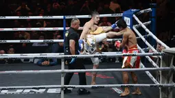 Petarung Malaysia, Ammarul Shafiq, melepaskan tendangan keras ke bagian rahang kiri petarung Indonesia, Serieal Effendy pada pertandingan Byon Combat Showbiz Vol. 6 di Tennis Indoor Senayan, Jakarta, Sabtu (22/10/2025). (Bola.com/M Iqbal Ichsan)
