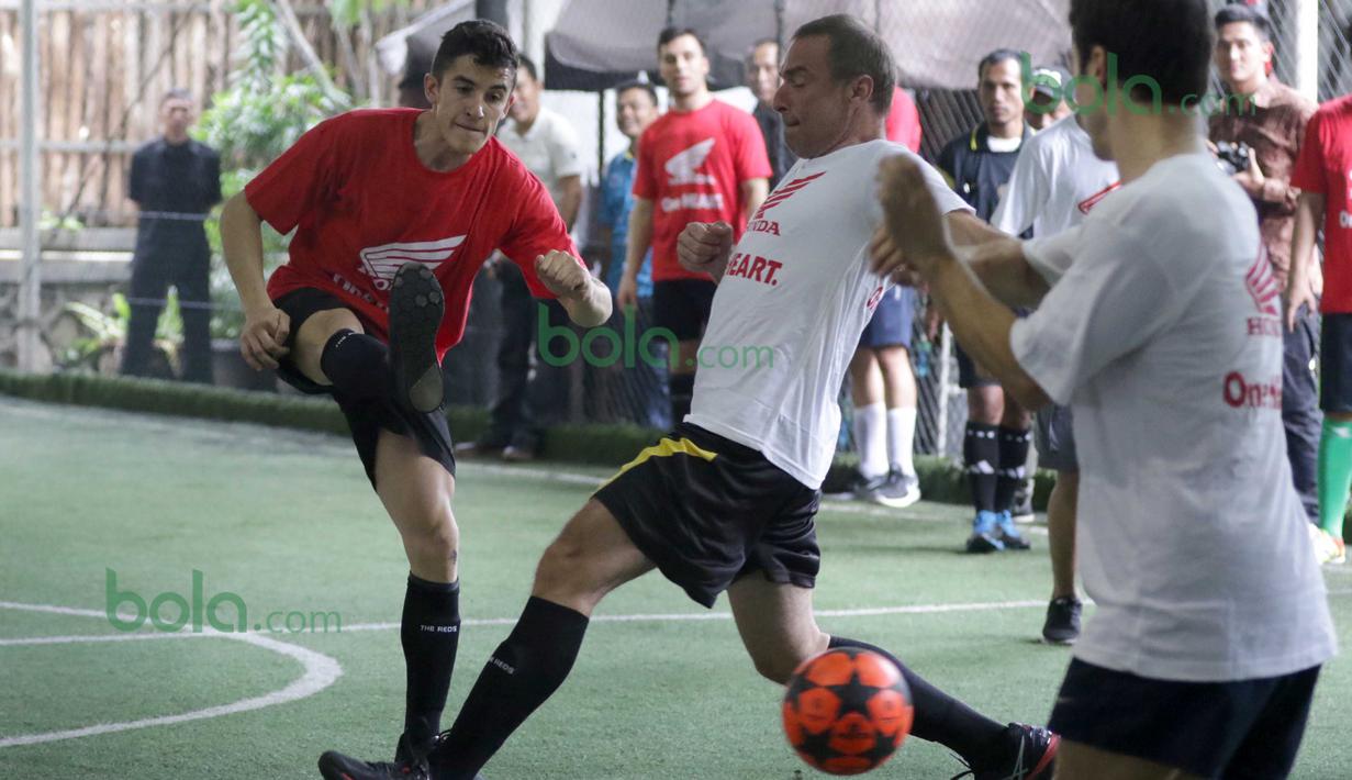 Marc Marquez (kirih) dari Tim Merah melepaskan tembakan saat dihadang Dani Pedrosa (kanan) di Lapangan Futsal Kuningan Village, Jakarta, Sabtu (13/2/2016). (Bola.com/Nicklas Hanoatubun)