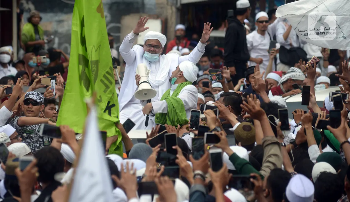 Rizieq Shihab menyapa massa pendukungnya saat tiba di kediamannya di Jalan Petamburan, Jakarta, Selasa (10/11/2020). Rizieq Shihab tiba di kediamannya usai pulang dari Arab Saudi. (merdeka.com/Imam Buhori)