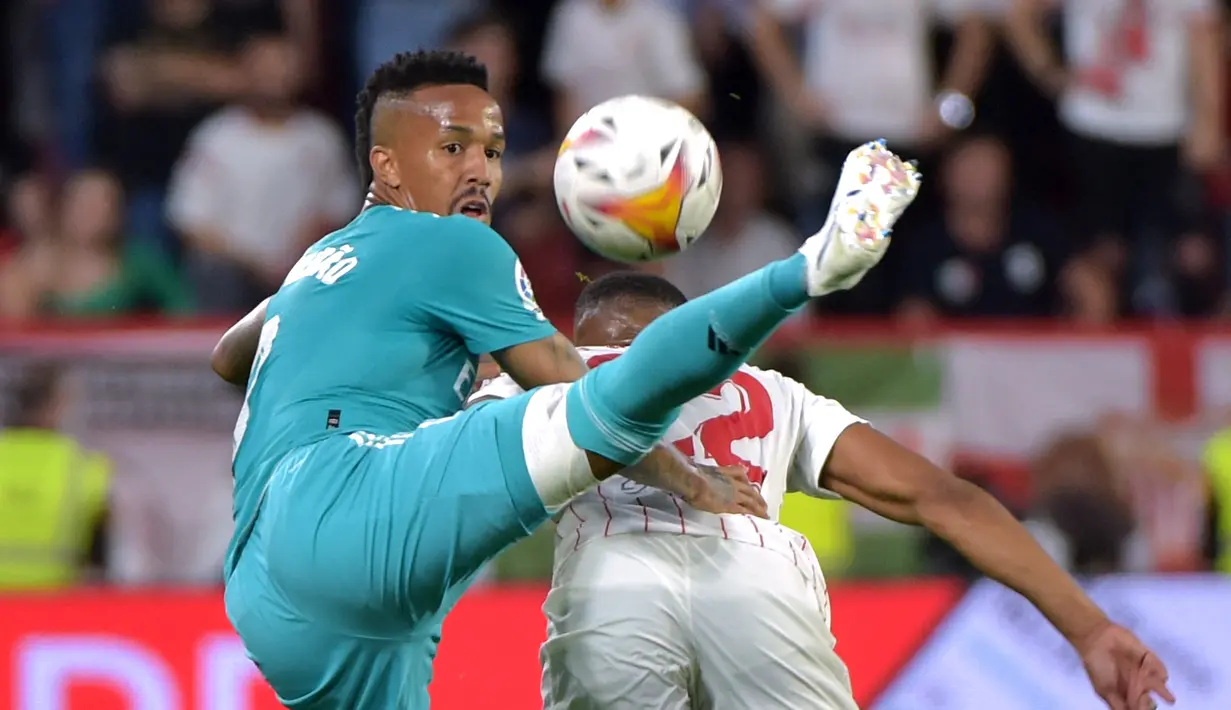 Bek Real Madrid Eder Militao (kiri) berebut bola dengan penyerang Sevilla Anthony Martial  pada lanjutan Liga Spanyol di stadion Ramon Sanchez Pizjuan, Senin (18/4/2022) dini hari WIB. Real Madrid sukses menaklukkan Sevilla 3-2. (CRISTINA QUICLER / AFP)