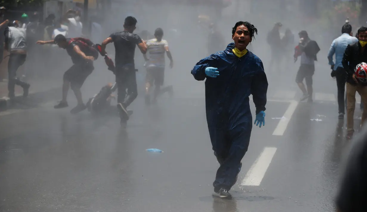 Polisi menembakkan meriam air dan gas air mata untuk membubarkan massa di Nepal (11/6/2020). Sekitar 1000 pemrotes berkumpul menuntut peningkatan pengujian dan dugaan korupsi oleh pejabat pemerintah saat membeli peralatan dan alat uji. (AP Photo/Niranjan Shrestha)