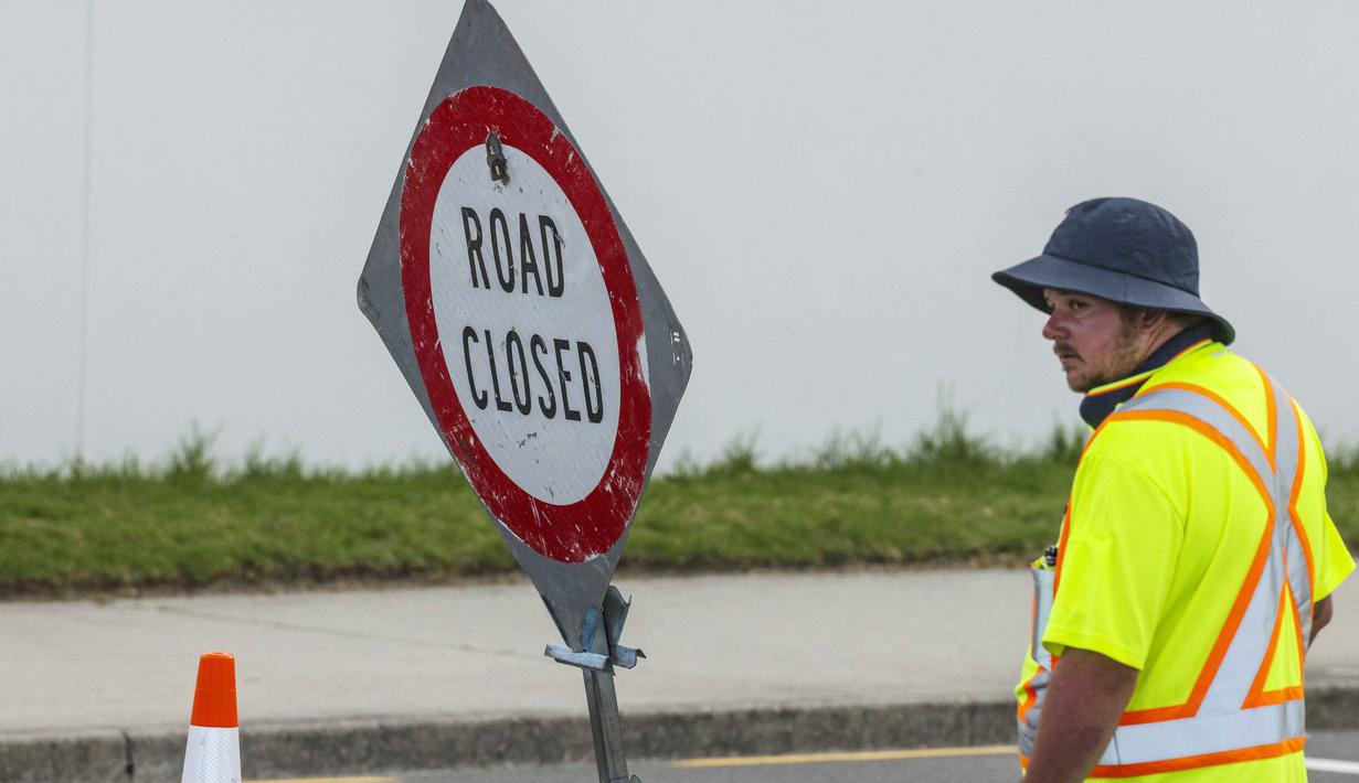 Sementara, pihak kepolisian setempat menyatakan lokasi perkemahan tersebut telah dikosongkan. Tampak dalam foto, petugas darurat menutup jalan setelah tanah longsor sementara pencarian sedang dilakukan oleh layanan darurat setempat untuk orang hilang di Gunung Maunganui, Tauranga, Selandia Baru pada Kamis 22 Januari 2026. (DJ MILLS/AFP)