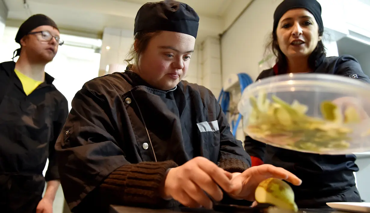 Seorang asisten memasak dengan down syndrome mempersiapkan menu makanan di dapur restoran "Le Reflet" di Nantes, Prancis Barat, 9 Februari 2017. Lelievre (26), mempekerjakan sejumlah karyawan yang memiliki down syndrome di restorannya. (LOIC VENANCE/AFP)
