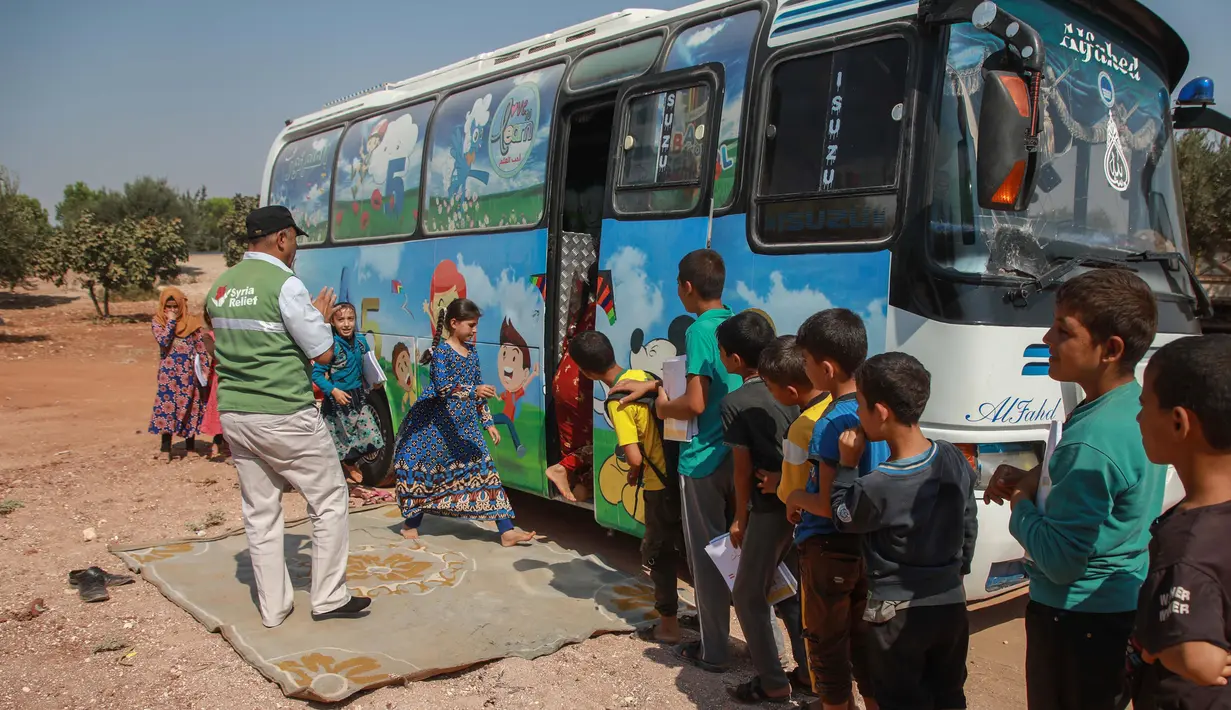 Anak-anak Suriah yang terlantar mengantre menaiki bus yang dikonversi menjadi ruang kelas di desa Hazano di barat laut Suriah (15/9/2019). Kelas di dalam bus ini hanya melayani usia mulai dari 5 hingga 12 tahun. (AFP Photo/Aaref Watad)