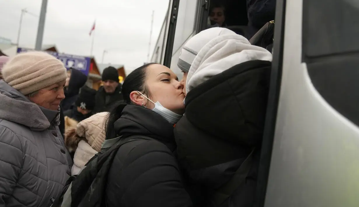 Seorang wanita mencium seorang anak ketika mereka mengantre untuk naik bus setelah meninggalkan Ukraina di perbatasan di Medyka, Polandia, 4 Maret 2022. (AP Photo/Markus Schreiber)