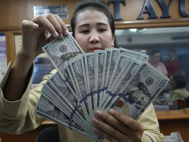 Teller tengah menghitung mata uang dolar di penukaran uang di Jakarta, Junat (23/11). Nilai tukar dolar AS terpantau terus melemah terhadap rupiah hingga ke level Rp 14.504. (Liputan6.com/Angga Yuniar)