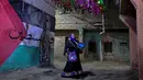 Dulu, petugas ini ditunjuk secara resmi untuk memastikan tidak ada warga yang melewatkan sahur. Tampak dalam foto, Dalal, seorang wanita Mesir 'musaharati', berdiri di depan grafiti yang menggambarkan bendera Palestina di sepanjang jalan sambil memukul gendang dan menyerukan umat Muslim untuk bangun dan makan sahur selama bulan suci Ramadan di distrik Hadayek el-Maadi, selatan Kairo pada Minggu 1 Maret 2026. (Khaled DESOUKI/AFP)