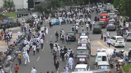 Sejumlah kendaraan dan massa demo 2 Desember melintasi jalan kawasan Tanah Abang menuju Monas, Jakarta, Jumat (2/12). Mereka terlihat berbondong-bondong berjalan kaki untuk mengikuti demo 2 Desember di Lapangan Monas. (Liputan6.com/Helmi Afandi)