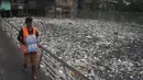 Seorang pria membawa botol air melintasi jembatan di sebelah tumpukan sampah yang mengambang di Sungai Negro, yang permukaan airnya naik karena hujan, di Manaus, negara bagian Amazonas, Brasil, Senin (6/6/2022). (AP Photo/Edmar Barros)