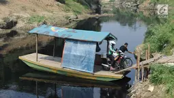 Pengendara motor menggunakan jasa penyeberangan perahu eretan di Sungai Cileungsi pebatasan Kabupaten Bogor-Kabupaten Bekasi, Bojong Kulur, Kabupaten Bogor, Jawa Barat, Selasa (23/7/2019). Perahu eretan tersebut digunakan warga sebagai jalan alternatif untuk menyeberang. (merdeka.com/Arie Basuki)