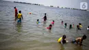 Anak-anak berenang saat petugas (kiri) mencari ubur-ubur di Pantai Lagoon, Ancol Taman Impian, Jakarta, Rabu (9/10/2019). Pihak Ancol telah memasang jaring agar ubur-ubur itu tidak sampai ke tempat warga yang sedang berenang. (Liputan6.com/Faizal Fanani)