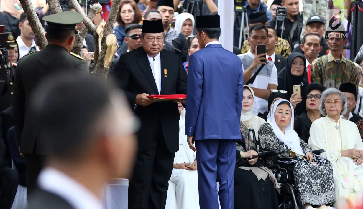 Presiden Joko Widodo atau Jokowi menyerahkan bendera Merah Putih kepada presiden ke-6 RI Susilo Bambang Yudhoyono (SBY) di ujung acara pemakaman Ani Yudhoyono di TMP Kalibata, Jakarta, Minggu (2/6/2019). Upacara pemakaman Ani Yudhoyono berlangsung khidmat. (Liputan6.com/JohanTallo)