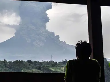 Penduduk desa melihat asap abu vulkanik Gunung Sinabung dari kota Karo (6/4). Gunung Sinabung di Kabupaten Karo, Sumatera Utara, kembali meletus, pada Jumat (6/4/2018) pukul 16.07 WIB. (AFP Photo/Anto Sembiring)