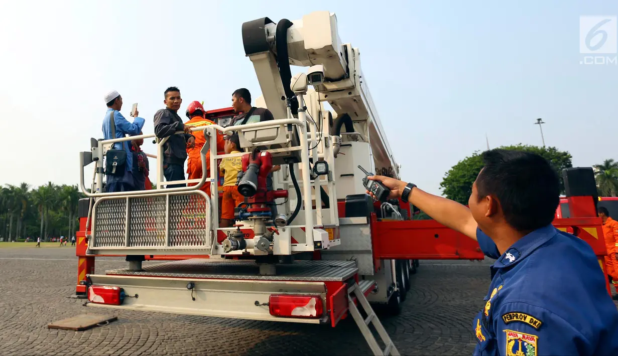 Petugas pemadam kebakaran bersiap mengantar pengunjung menaiki Bronto Skylift di Monas, Jakarta, Minggu (23/11). Dengan naik Bronto Skylift pengunjung bisa melihat Monas dari dekat. (Liputan6.com/JohanTallo)