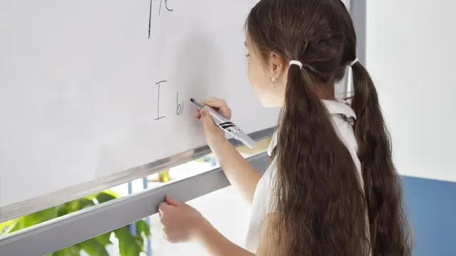 Seorang anak perempuan sedang menulis di papan tulis (Foto Dok: Freepik/freepik)