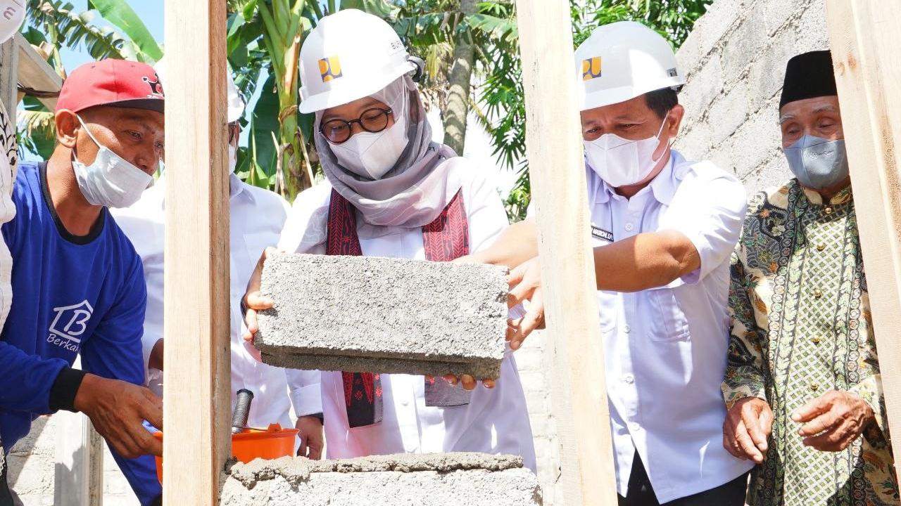 Bupati Banyuwangi Ipuk Fiestandaini (Tengah) memasang batako sebagai simbol dimulainya festival bedah rumah di Banyuwangi (Istimewa).
